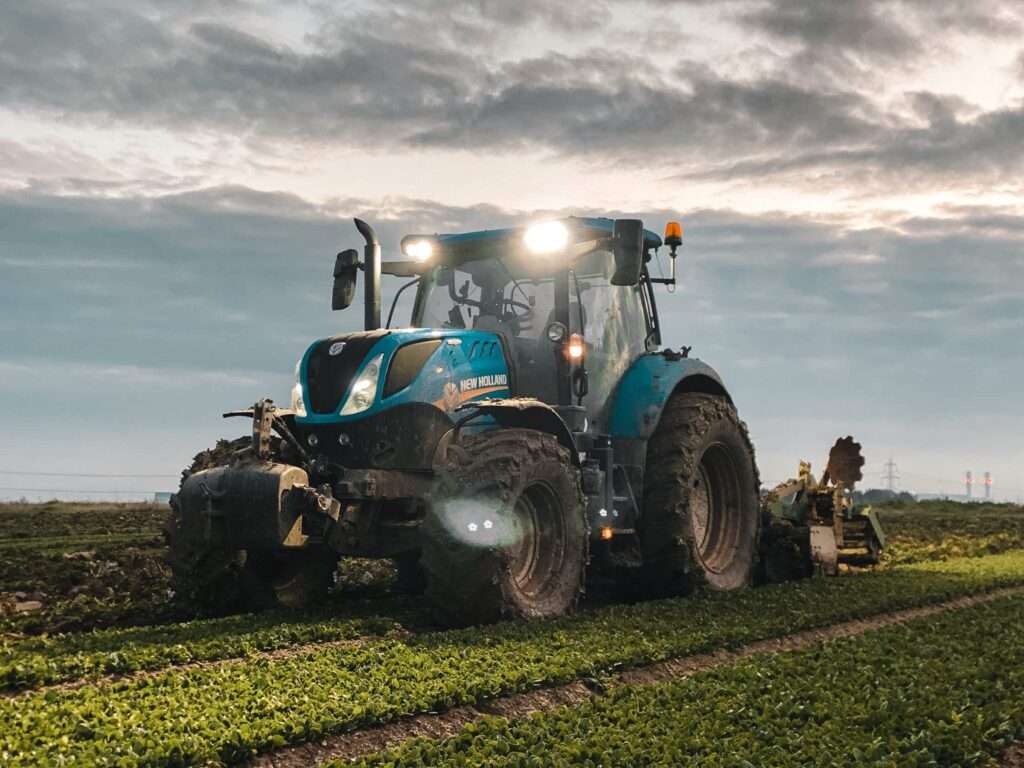 Blue tractor working on farmland – AspaGrow Machinery